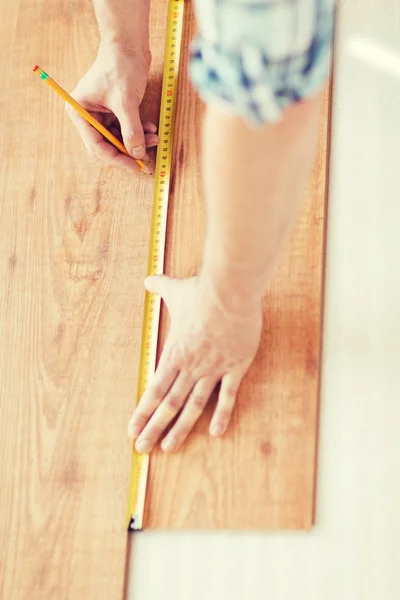 Close up of male hands measuring wood flooring — Stock Photo, Image