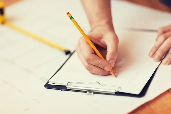 Close up of male hands writing in clipboard — Stock Photo, Image