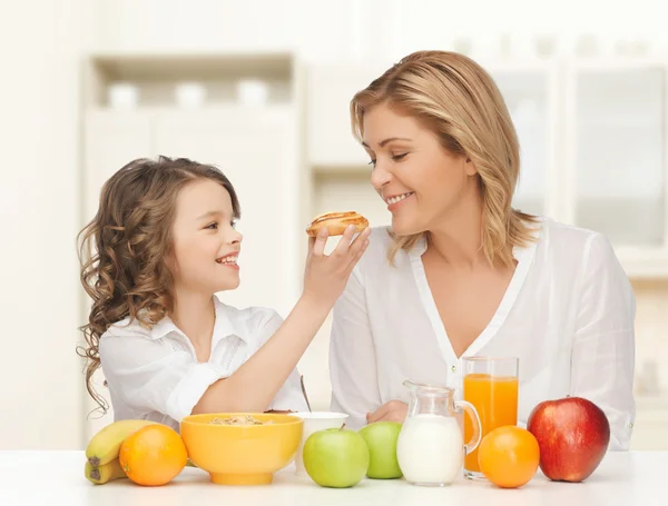 Happy mother and daughter eating breakfast — Stock Photo, Image