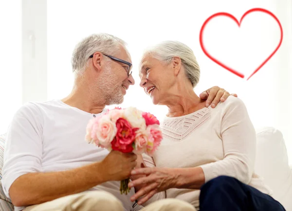 Happy senior couple with bunch of flowers at home — Stock Photo, Image