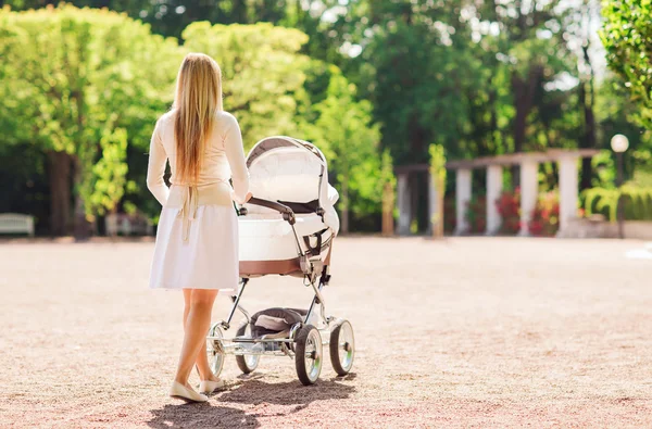 Gelukkig moeder met wandelwagen in park — Stockfoto