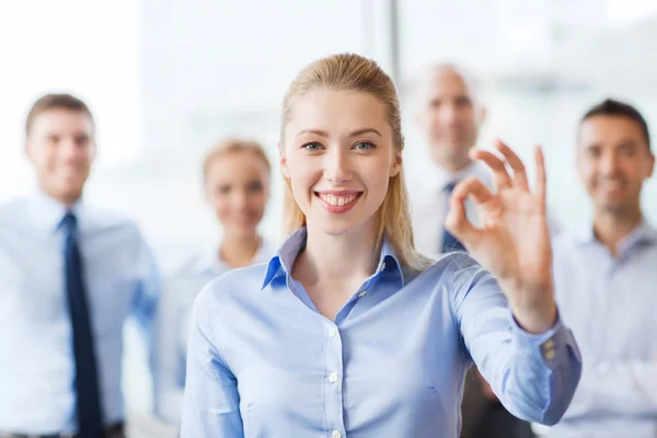 Sonriente mujer de negocios mostrando ok signo en la oficina —  Fotos de Stock