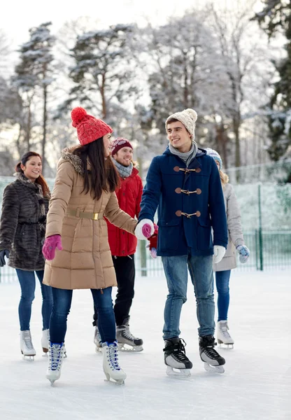 Happy vrienden schaatsen op de ijsbaan buitenshuis — Stockfoto
