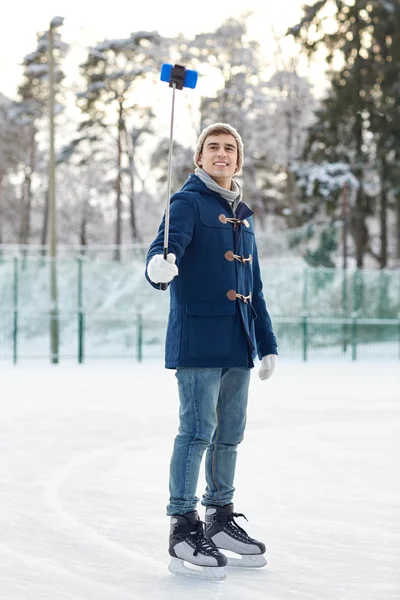 happy young man with smartphone on ice rink