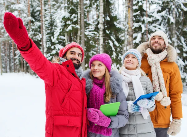 Lachende vrienden met tablet pc in winter forest — Stockfoto