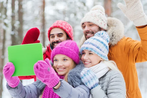 Amigos sorridentes com tablet pc na floresta de inverno — Fotografia de Stock