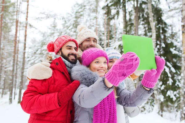 Smiling friends with tablet pc in winter forest — Stock Photo, Image