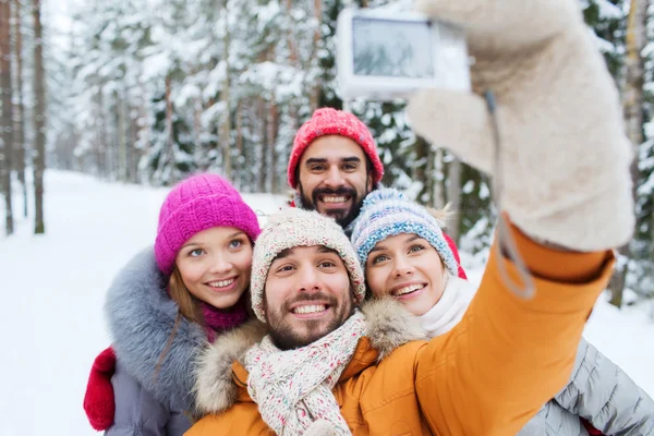 Amigos sonrientes con cámara en el bosque de invierno —  Fotos de Stock