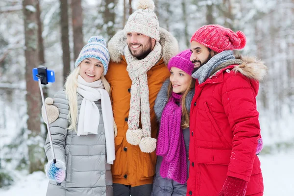 Smiling friends with smartphone in winter forest — Stock Photo, Image