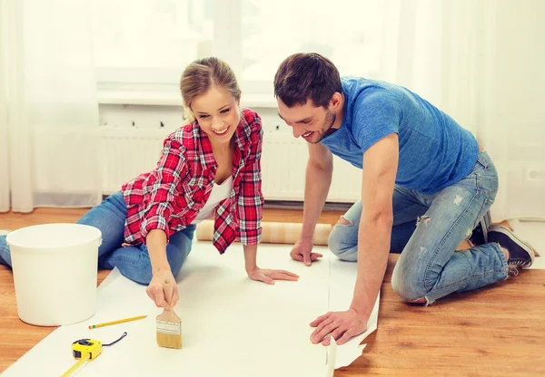 Smiling couple smearing wallpaper with glue — Stock Image Smiling couple smearing wallpaper with glue Stock Picture