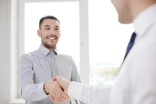 Twee Glimlachende zakenmensen schudden handen in office — Stockfoto