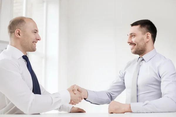 Двое улыбающихся бизнесменов пожимают друг другу руки в офисе — стоковое фото