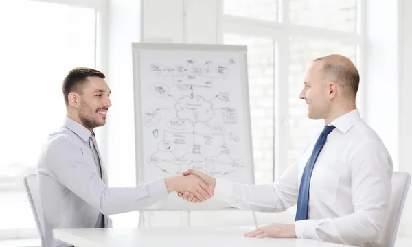 Dos hombres de negocios sonrientes estrechando la mano en la oficina —  Fotos de Stock