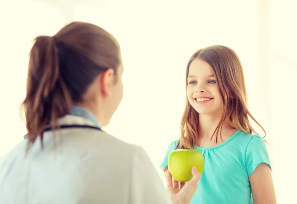 Kvinnliga läkare att ge apple till leende liten flicka — Stockfoto