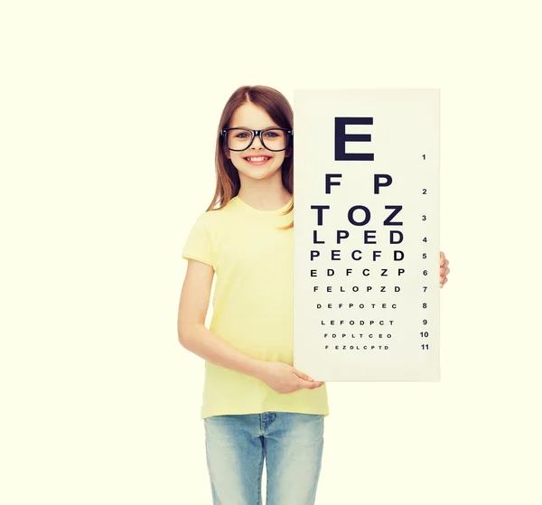 Маленькая девочка в очках с диаграммой проверки зрения — стоковое фото