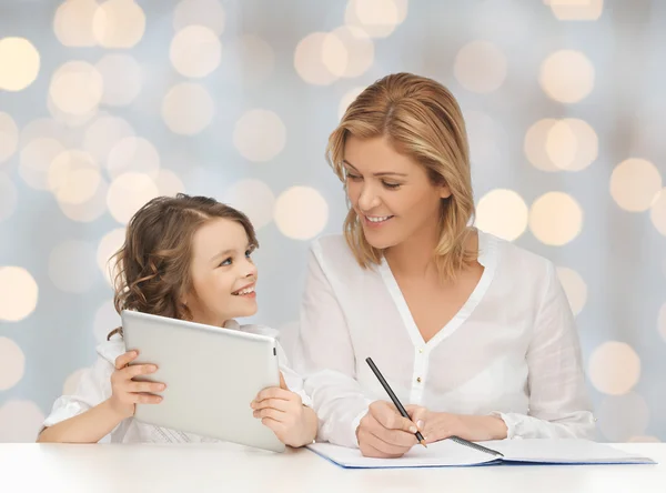 Mujer con cuaderno y niña sosteniendo la tableta pc —  Fotos de Stock