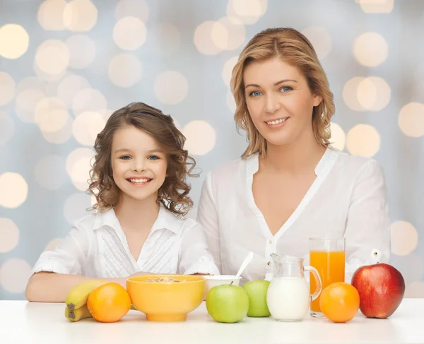 Happy mother and daughter eating breakfast — Stock Photo, Image