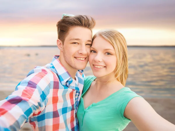 Smiling couple with smartphone on summer beach — Stock Photo, Image