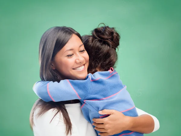 Mujer feliz y niña pequeña abrazándose en la escuela —  Fotos de Stock