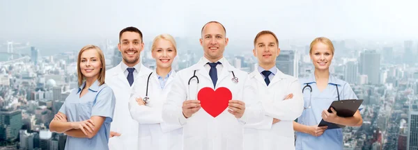 Grupo de médicos sorridentes com forma de coração vermelho — Fotografia de Stock