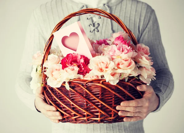 Hombre sosteniendo cesta llena de flores y postal —  Fotos de Stock