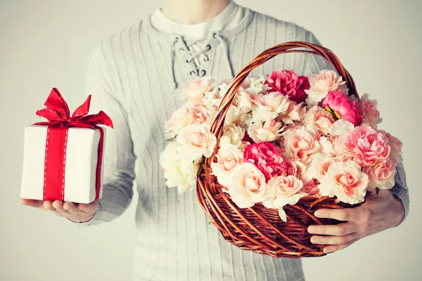 Man holding basket full of flowers and gift box — Stock Photo, Image