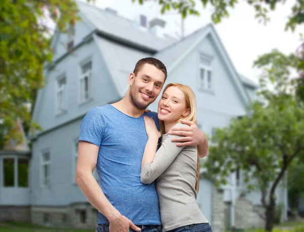 Sonriente pareja abrazando sobre casa fondo — Foto de Stock