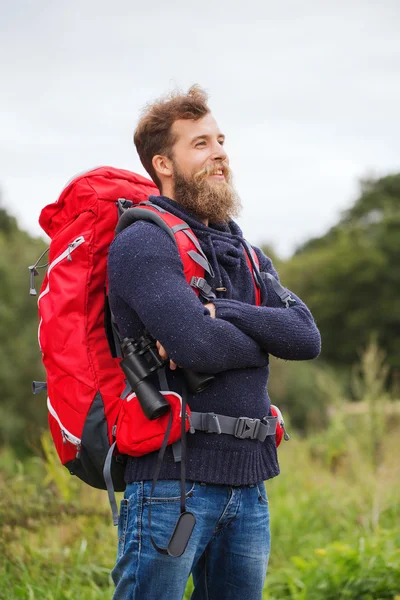 Glimlachende man met rugzak en verrekijker buiten — Stockfoto