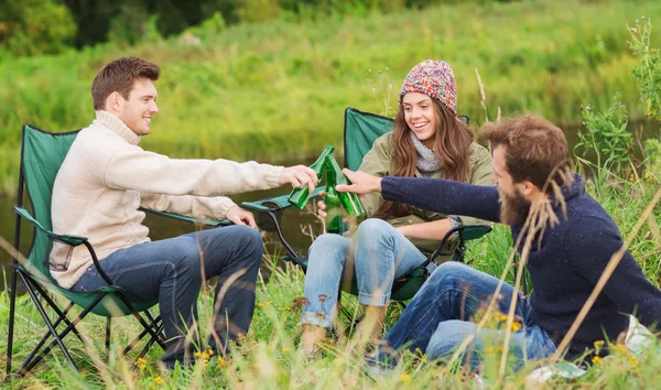 Группа улыбающихся туристов, пьющих пиво в кемпинге — стоковое фото