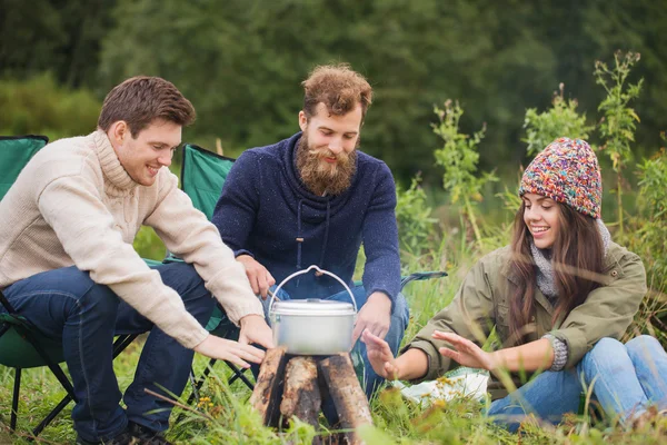 Grupo de amigos sonrientes cocinando comida al aire libre — Foto de Stock