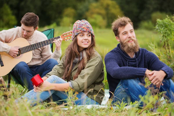 Group of smiling friends with guitar outdoors — Stock Photo, Image