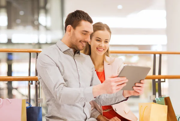 Casal com tablet pc e sacos de compras no shopping — Fotografia de Stock