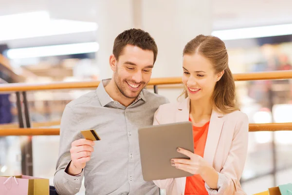 Pareja con tablet pc y bolsas de compras en el centro comercial — Foto de Stock