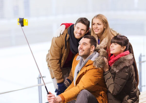 Happy friends with smartphone on skating rink — Stock Photo, Image