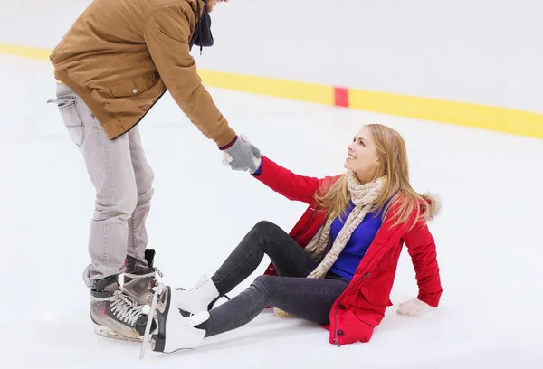 Homem ajudando as mulheres a levantar-se na pista de patinação — Fotografia de Stock