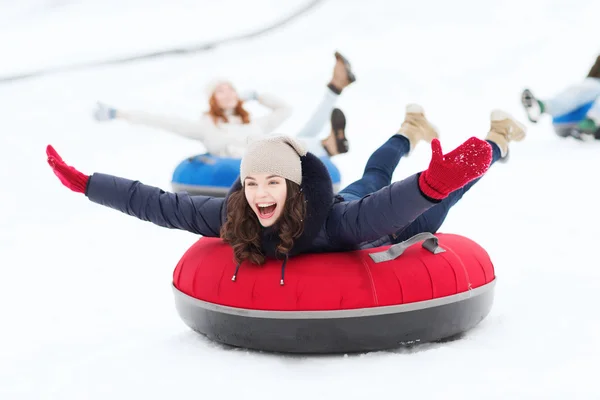 Groupe d'amis heureux glissant vers le bas sur des tubes à neige — Photo