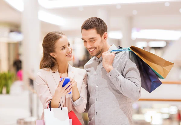 Couple with smartphone and shopping bags in mall Stock Image