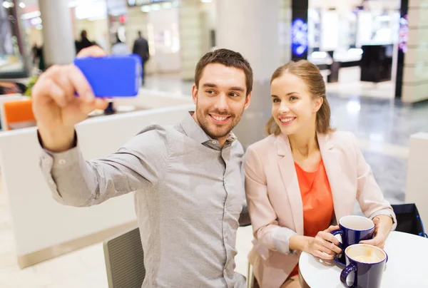 Happy couple with smartphone taking selfie in mall — Stock Photo, Image