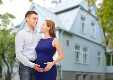 happy young family expecting child over house clipart