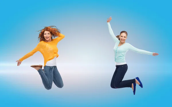 Sonrientes mujeres jóvenes saltando en el aire — Foto de Stock