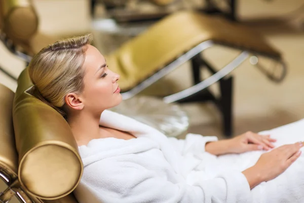 Beautiful young woman sitting in bath robe at spa — Stock Photo, Image