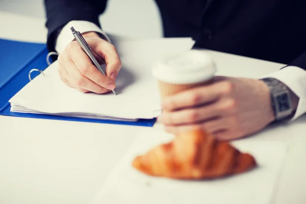 Uomo d'affari con caffè che scrive qualcosa — Foto Stock