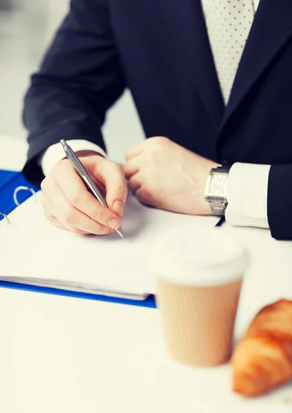 Zakenman met koffie schrijven iets — Stockfoto