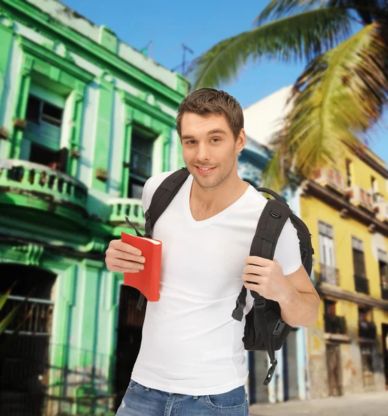 Счастливый молодой человек с рюкзаком и книгой путешествия — стоковое фото