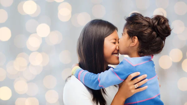 Glückliches kleines Mädchen, das seine Mutter umarmt und küsst — Stockfoto