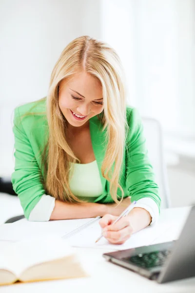 Smiling student girl writing in notebook — Stock Photo, Image