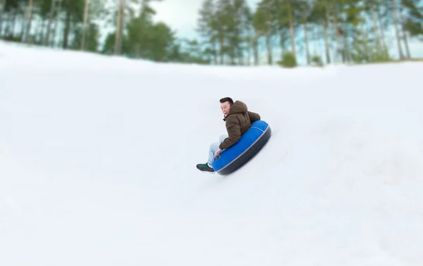 Jovem feliz deslizando para baixo no tubo de neve — Fotografia de Stock