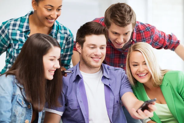 Studenti při pohledu do smartphone ve škole — Stock fotografie