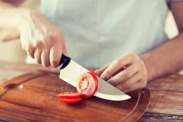 Male hand cutting tomato on board with knife — Stock Photo, Image