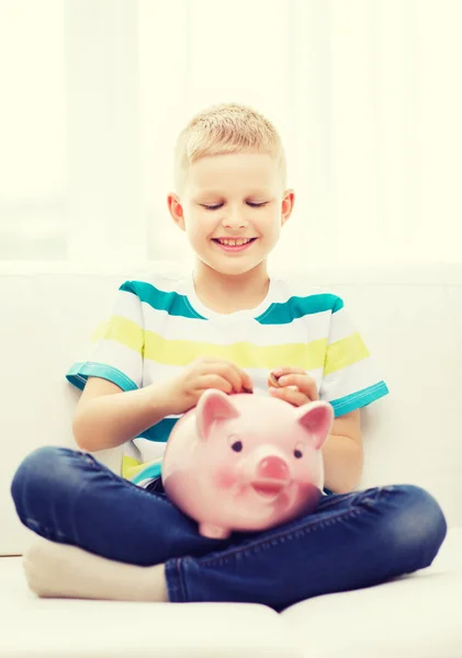 Lachende jongetje met piggy bank thuis — Stockfoto